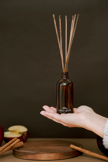 A hand holds an amber glass bottle of a